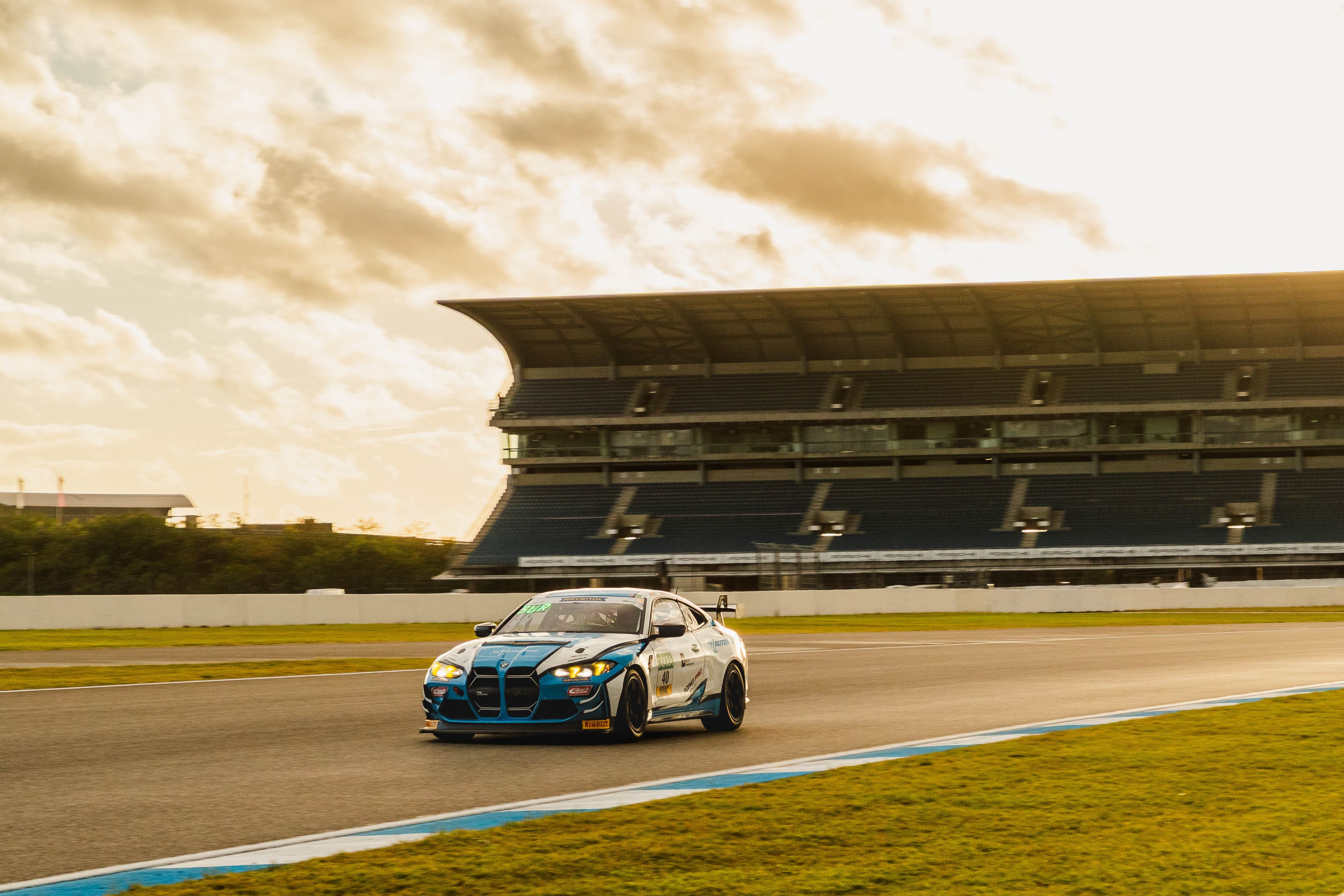 The #40 BMW small against the full Hockenheim grandstand under a dramatic sky